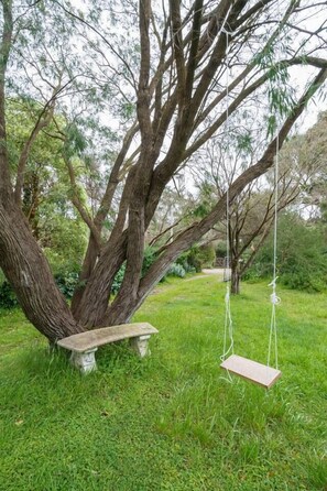 The lush backyard offers a tree swing and bench to enjoy the great outdoors.