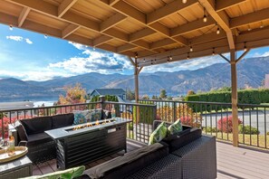 Outdoor covered deck with lake views, lounge seating, fire table and hot tub