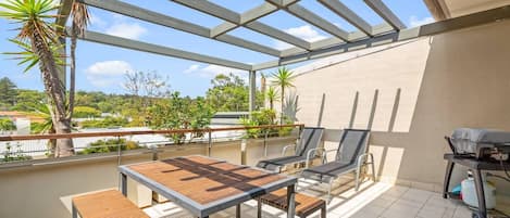 Enjoy the outdoor balcony flowing seamlessly from the living area that is complete with a barbeque, table, and chairs to dine and relax.