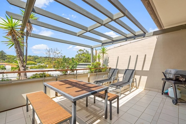 Enjoy the outdoor balcony flowing seamlessly from the living area that is complete with a barbeque, table, and chairs to dine and relax.