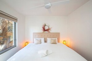  The light and airy bedroom features a king-size bed, with high ceilings and large windows creating a sense of spaciousness. 
