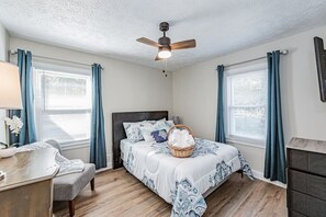 Secondary bedroom with queen bed, flat-screen Roku TV, and ceiling fan on first floor.