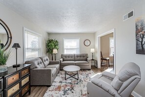 Primary living room with plush seating, reclining chair, tons of natural light, and a 50" flat-screen Roku TV.