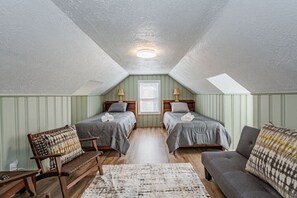 Third bedroom on the second floor with two twin beds, seating area, cape cod ceiling, and flat-screen Roku TV.