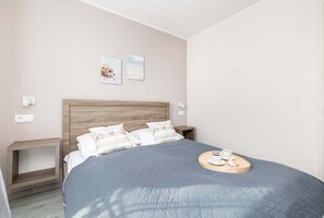 A cozy bedroom with a large bed, blue bedding, and soft lighting.

