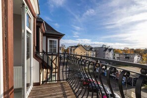A charming balcony with a black railing, overlooking a scenic European street.

