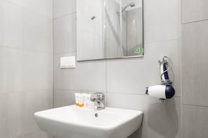 A sleek bathroom with a minimalist sink, a large mirror, and gray tiles.

