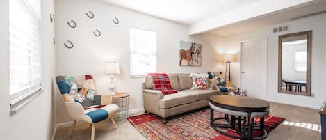 Living room with cozy couch set and mirror and airy windows