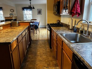 Galley kitchen features a raised counter on the island, and a large pantry. 