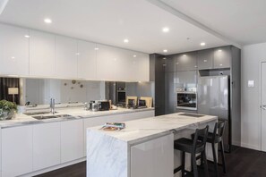 The modern, marble-topped kitchen is fully equipped for home-cooked feasts and quick bites at the breakfast bar.