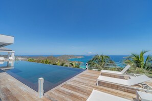 Expansive terrace with deck loungers, long heated pool facing the panoramic views. Outdoor lounge area under the gazebo.