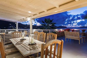 On the covered terrace, large wooden dining table for 8 guests.