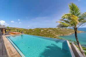 Heated pool surrounded by a spacious sun terrace with deckchairs. An outdoor lounge area with large sofas is on the covered terrace. Spectacular view of the bay of Marigot. 