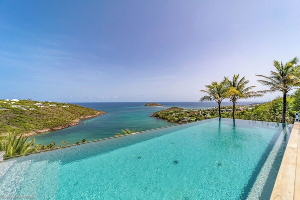 Heated pool surrounded by a spacious sun terrace with deckchairs. An outdoor lounge area with large sofas is on the covered terrace. Spectacular view of the bay of Marigot. 