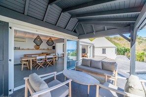 Coin lounge sur la terrasse couverte, face à la vue et donnant sur la piscine.