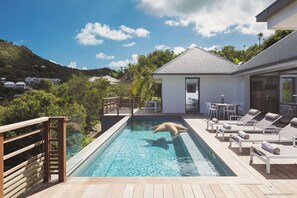 Belle piscine face à la vue panoramique, grande terrasse avec chaises longues et coins lounge. Barbecue à gaz.