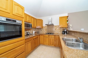Kitchen equipped with breakfast bar, electric oven, gas stove, microwave, fridge and freezer with ice maker, dishwasher, blender, electric fruit squeezer, electric kettle, Nespresso coffee machine and regular filter machine. Inside dining table for 4 gues