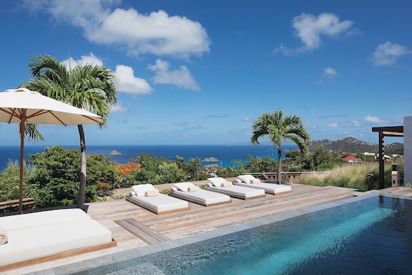 Large infinity pool (8m x 3,5m) with wading area and stairs, surrounded by a spacious wood deck with 6 lounge chairs. Ocean & sunset view.