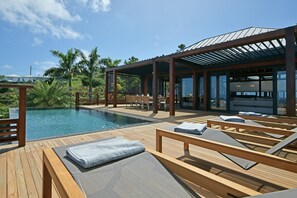 Heated pool surrounded by a spacious sun terrace with deckchairs. An outdoor lounge area with large sofas is on the sunny terrace. Spectacular view of the bay of marigot. 