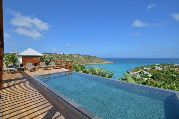 Heated pool surrounded by a spacious sun terrace with deckchairs. An outdoor lounge area with large sofas is on the sunny terrace. Spectacular view of the bay of marigot. 