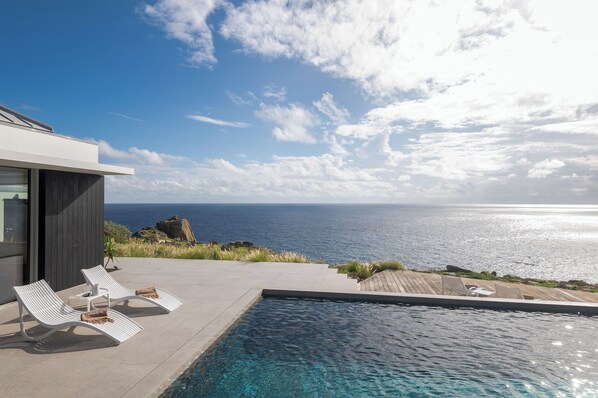 Beautiful heated pool surrounded by a sunny deck with deckchairs, facing the breathtaking panorama.