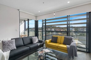 The light-filled living area features a sofa and TV where guests can kick back with a movie after a day of work or sightseeing. 
