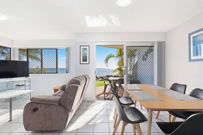The light-filled dining space includes a six-seater table and views overlooking the water. 
