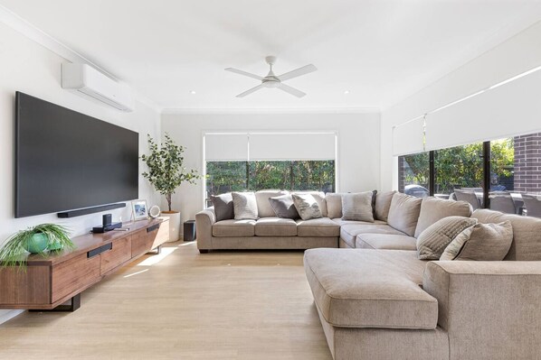 Stretch out in the living room on the extensive lounge space that wraps around the room. Bright windows open up to the garden. A wide HD TV with Netflix and Chromecast is mounted on the wall with a sound bar. Enjoy relaxing with loved ones. 