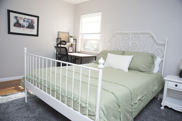 Bedroom with queen size bed and desk.