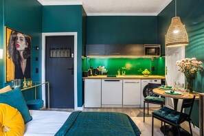 A compact living space with a kitchenette, teal accents, and a cozy dining area.

