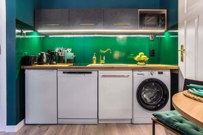 A sleek kitchen with under-cabinet lighting, white cabinets, and a washing machine.

