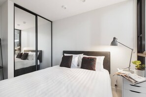 The bedroom is complete with a plush queen bed, mirrored robe and floor-to-ceiling windows that pour in natural light