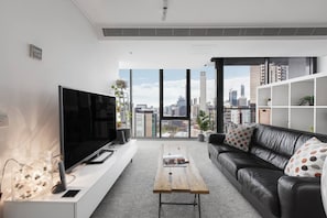 The living area offers skyline views, plenty of natural light and a plush leather couch situated in front of a flatscreen TV.