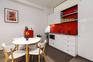 An indoor dining set that can seat four sits alongside a contemporary kitchen with a quirky red splashback