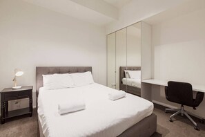 A second bedroom has a queen bed, built-in mirrored cupboard, and a working space furnished with a desk and chair