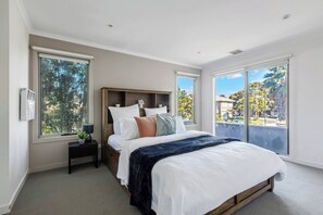 The primary bedroom has a queen bed, ensuite bathroom, flat-screen TV, and room darkening shades.
