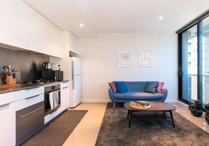 A contemporary and compact kitchen lines the wall near the living area and is fully-equipped with modern appliances