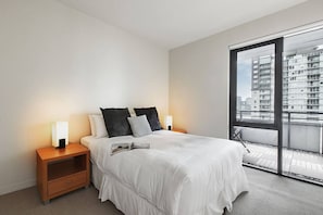 In the bedroom, there is a comfortable queen-sized bed topped with premium, hotel-style linens, and direct balcony access.