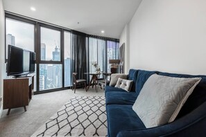 The open living and dining includes a comfortable velvet couch in front of the TV.