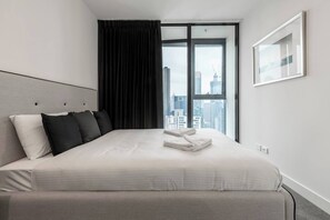 The bedroom is fitted with a queen sized bed and a private balcony with city views over Melbourne.