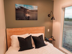 Bedroom: Queen bed with AC, TV, and outdoor view
