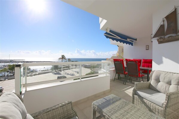 Large balcony with outdoor dining area for four guests, relaxing seaters and sea views