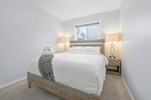 Drift off in comfort with our queen bed, outfitted with fresh, plush bedding and accented by modern dimmable night lamps.