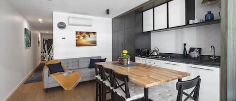 A compact but open floor plan makes use of every nook and cranny, with a high-top table offering extra benchtop space and four stools so the entire group can come together for a meal.