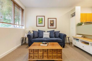 Staying in? A bright living room features timber furniture, a plush two-person couch and a large TV for your comfort
