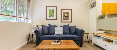 Staying in? A bright living room features timber furniture, a plush two-person couch and a large TV for your comfort
