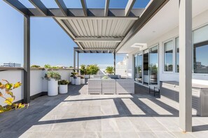 A huge outdoor terrace features stylish and functional furnishings with a treetop view of the surrounding neighbourhood and city skyline beyond