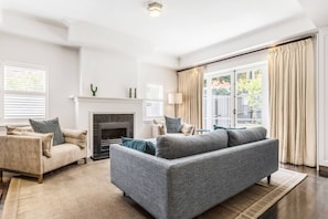  An inviting lounge area features a large sofa and comfy armchairs to settle in with a movie or a book, with large windows offering views of the courtyard. 
