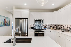 Step into this stunning kitchen featuring sleek white cabinets & a charming tile design in several hues of blue. Cooking has never been more delightfu