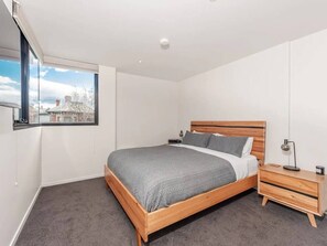 Unwind in the first bedroom, furnished with a queen bed, built-in wardrobes, panel heater, and a mounted TV. This serene space ensures a restful night's sleep after a day of exploring the city.